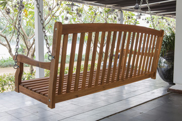 The brown wood swing in the backyard.