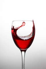 Splash of red wine in a crystal glass on white background close-up