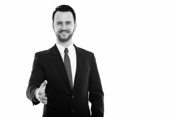 Studio shot of young happy businessman smiling while giving handshake
