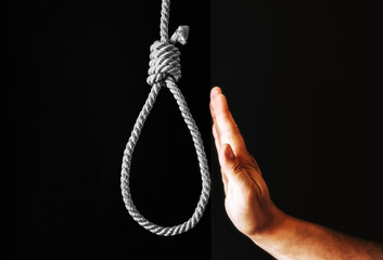 Hand near the noose on black background. Stop suicide concept. Hanging because of work stress....