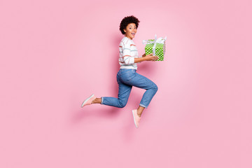 Full length body size photo of excited fast quick crazy funny girlfriend black skinned cute cheerful wearing jeans denim striped sweater holding giftbox with hands isolated pastel color background