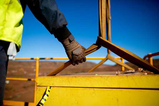 Rigger hand construction worker wearing heavy duty glove holding safety control a two tones yellow lifting sling which its connecting to the load while crane is lifting construction building site 
