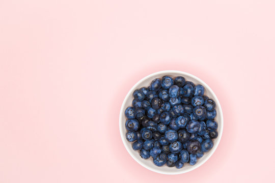 blueberries in a bowl. Blueberries on a colored background. place for writing. view from above. sprinkle in pasuda. natural berries. Top view of fresh ripe blueberries in a bowl