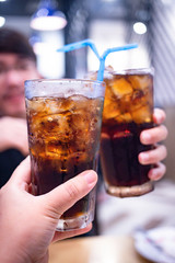 Young couple with glasses of refreshing cola with ice in restaurant, Two glasses of cola with ice