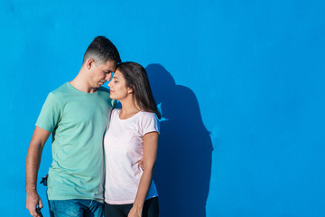 Naklejka premium Young couple smiling standing together isolated on blue background. People and emotions concept with copy space.