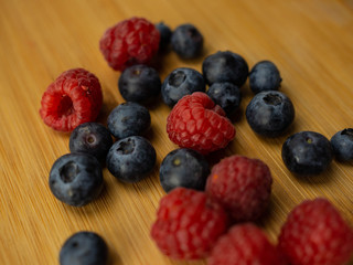 Owoce leśne, maliny, borówki leżące na drewnianej desce. Zbliżenie. © PhotoHunter
