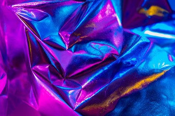 Blue-lilac background. Shiny iridescent fabric with beautiful pleats. Foil background in different shades. A brocade tablecloth lay on the table. Blue rainbow background.
