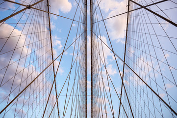 Close-up abstract view of criss-crossed steel suspension cables of the Brooklyn Bridge under scenic sunset skies
