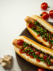 Pyszne domowe hot dogi. Parówka, bułka, szczypiorek, pomidor na białym tle. Widok z góry.