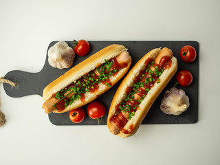 Pyszne domowe hot dogi. Parówka, bułka, szczypiorek, pomidor na białym tle. Widok z góry.