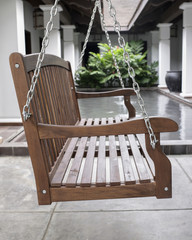 The detail of brown wood swing in the backyard.