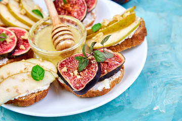 Bruschetta and Crostini with pear, ricotta cheese, honey, figs, nuts and herbs. Breakfast toasts or snack sandwiches. Antipasto. Italian food. Top view. Copy space.