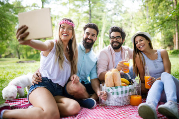 Happy friends in the park having picnic on a sunny day.