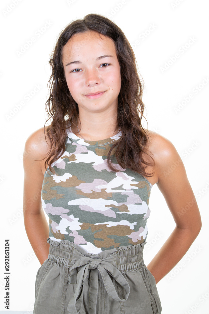 Wall mural portrait of a smiling young woman teenager girl standing with arms folded back behind