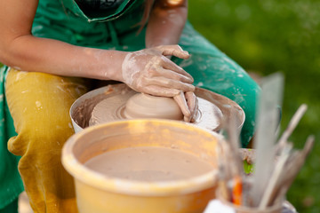 Hand craft making pottery on wheel. Female hands mold ceramic plate from clay (pot).