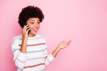 Photo of pretty excited dark skin lady holding telephone talking with best friend wear white striped pullover isolated pastel pink color background