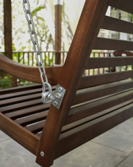 The detail of brown wood swing in the backyard.