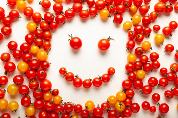 Red and yellow cherry tomatoes, fresh bright organic vegetables. Smiling face.