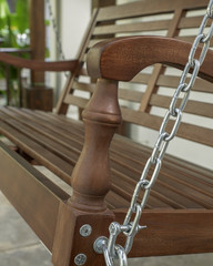 The detail of brown wood swing in the backyard.
