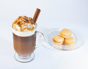 Coffee, cappuccino in a glass, Irish glass. Whipped cream sprinkled with ground nuts and chocolate chips, a cinnamon stick. Glass plate, pasta cakes. The photo.