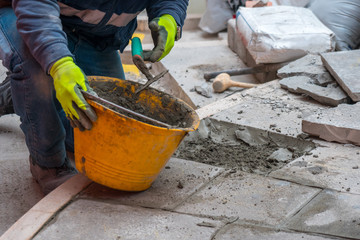 A worker strengthens the stones of the stairs with trowel, sand and concrete