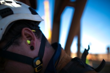 Miner worker wearing a ear plug noise safety protection when working near  operating life plant...