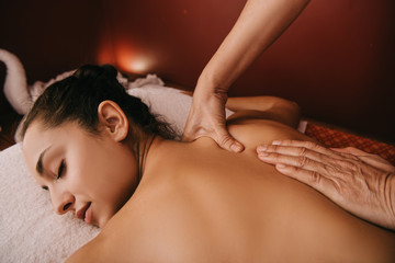 Obraz na płótnie Canvas cropped view of masseur doing back massage to woman on massage mat