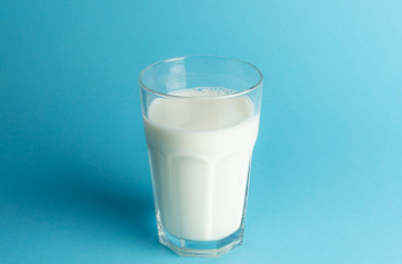 A glass of fresh milk on blue background, copy space