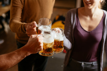 Group of happy friends drinking and toasting beer at bar 