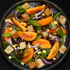 Salad with yellow tomatoes, sweet corn, basil and croutons, panzanella,  top view 