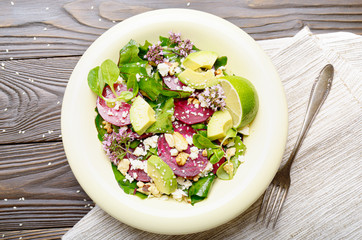 Top view at mediterranean roasted beet salad with avocado walnuts feta cheese oregano and mash leaves on dinner table