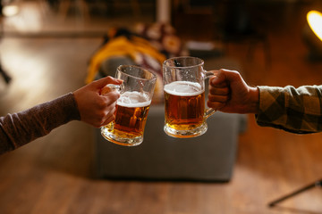 Close-up of two people toasting with beer.