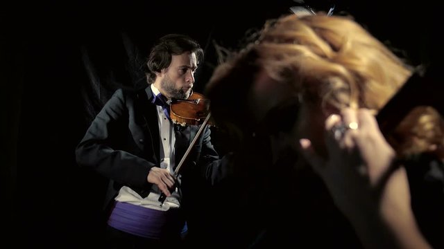 Violinist man and cellist woman. Сlassical music performance, black background