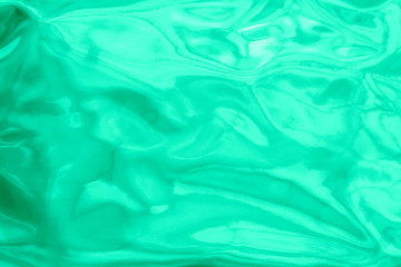 Holographic wrinkled abstract foil texture. Glittering blurred surface pack. Green mint bright holographic foil background.