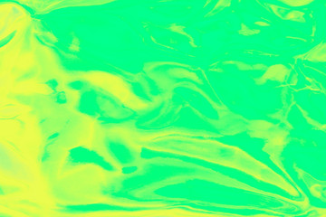 Holographic wrinkled abstract foil texture. Glittering blurred surface pack. Green and yellow bright holographic foil background.