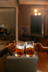 Close-up of two people toasting with beer.
