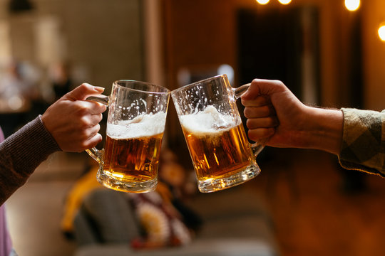 Close-up of two people toasting with beer.