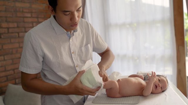 asian father change baby diapers when little baby daughter lying on the crib