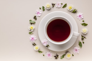 Fragrant herbal tea in a white ceramic cup and saucer. Flower circle pattern on a beige background. Flower tea concept. Tea bag. Top view