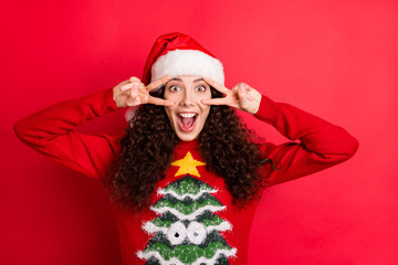 Close-up portrait of her she nice attractive lovely charming cheerful cheery crazy wavy-haired Santa girl showing v-sign near eye isolated on bright vivid shine vibrant red color background
