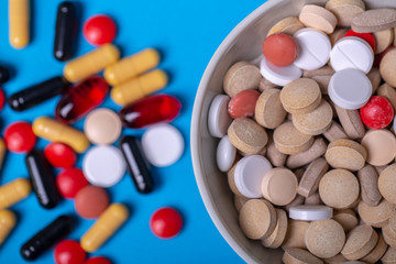 Top view with a bowl of multi-colored pills and in the background