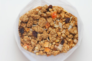 Granola with fruits and nuts in a transparent plastic bag. Baked muesli mix. Super food concept. Breakfast cereals. Kids diet. White isolation background.