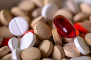 Close up with a red pill among multicolored pills