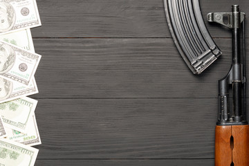 one hundred dollar notes on a wooden background with a place for copy space and Soviet automaton AK 47