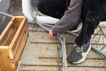 Man is laying empty conduits for power supply in a house under construction