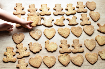 Homemade brown christmas cookies in various form baked by little hand of child. Gingerbreads on the wooden background.