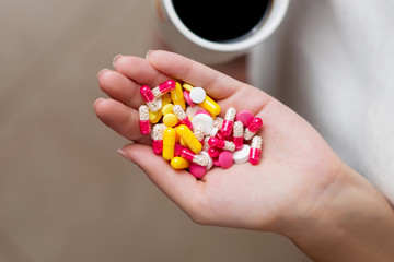 a palm full of pills and a cup of coffee is visible nearby