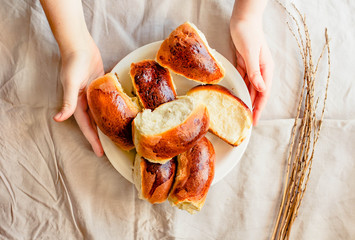 Young woman hands holding freshly Russian traditional patties with stuffing on wooden desk and white linen tablecloth.