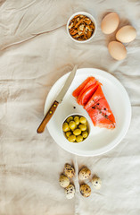 Salt Salmom with quail eggs, nuts and olive on a white linen tablecloth. Top view. Paleo diet. Healthy high protein and low carbohydrate products concept. Copy space