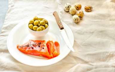 Slices of Salted Raw fish fillet with olive, quail eggs on white plate. Selection of good fat sources - healthy eating concept. Ketogenic diet concept. Selective focus